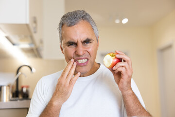 Toothache concept. Adult man broke a tooth when he bit an apple. Visit your dentist regularly Man...