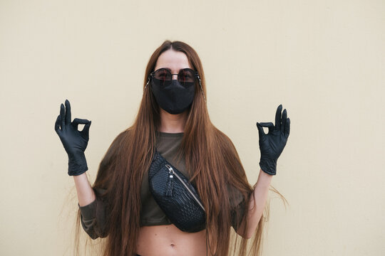 Young female wearing black face mask, latex gloves and sun glasses