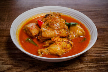 Ayam Kalio Padang or wet saucy chicken rendang on wooden background.