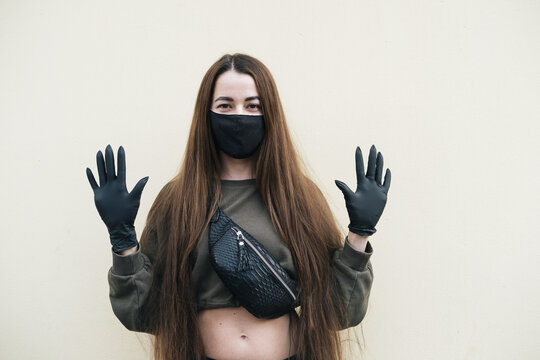 Young woman wearing black face mask and latex gloves