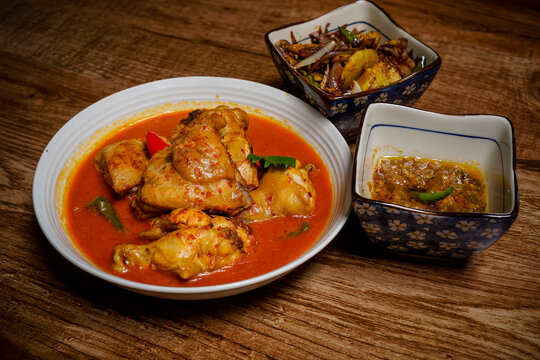 Ayam Kalio Padang Or Wet Saucy Chicken Rendang With Side Dishes On Wooden Background.