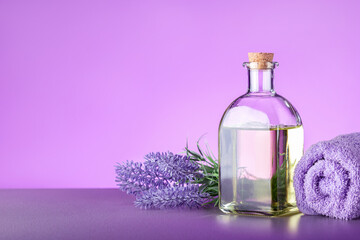 Obraz na płótnie Canvas Glass bottle of Lavender essential oil with fresh lavender flowers and towel on the table with place for text.
