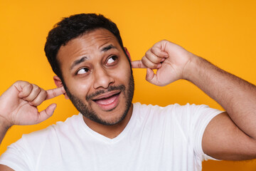 Asian young unshaven man plugging his ears with fingers