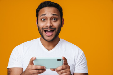 Asian excited unshaven man playing online game on mobile phone
