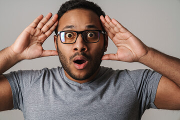 Asian unshaven scared man touching his head and looking at camera