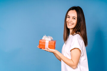 Happy girl hold a present box isolated on blue background