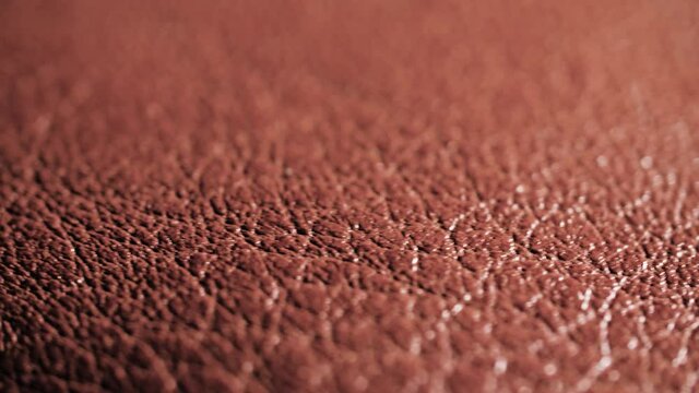 4K Rotating extreme close-up of real organic brown leather texture. Natural background pattern of animal skin used in fashion and clothing industry. Detail of shoe, purse, or other accessory.