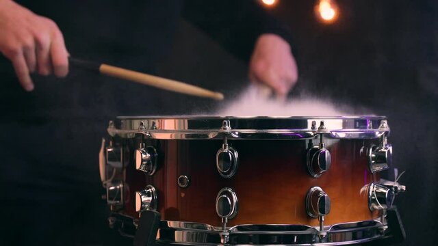 Man playing on snare drum with drumsticks. Closeup.
