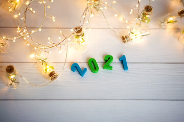 Figures 2021 on a background of garlands and bokeh. Blue, green, gold, white,  yellow background. New year banner