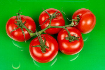several large red tomatoes close-up on a green background
