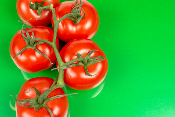 several large red tomatoes close-up on a green background