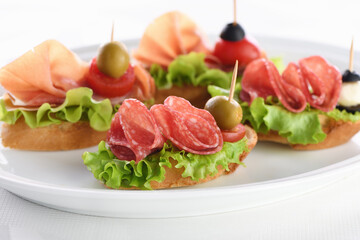Tender baguette canapes with Leaf lettuce, salami or Parma ham, tomatoes, mozzarella and olive. Delicacy assorted platter for at the party.