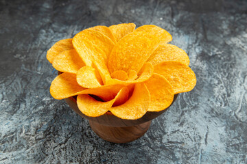 Close up view of potato chips decorated like flower shaped in a brown bowl on gray background