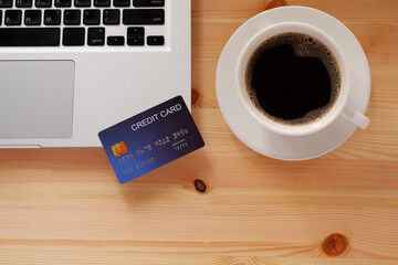 Credit card and laptop computer with black coffee in white cup. Concepts of online shopping or delivery where consumers can buy products directly from home or work.