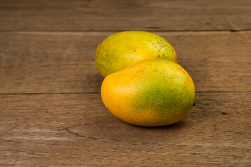 Ripe mango on wooden table. Tropical fruit. Two fresh mango. Ripe yellow mangoes on wooden background
