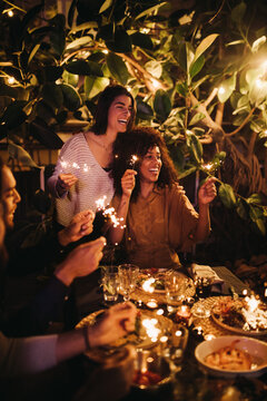 group of friends cheering with sparklers on party together 