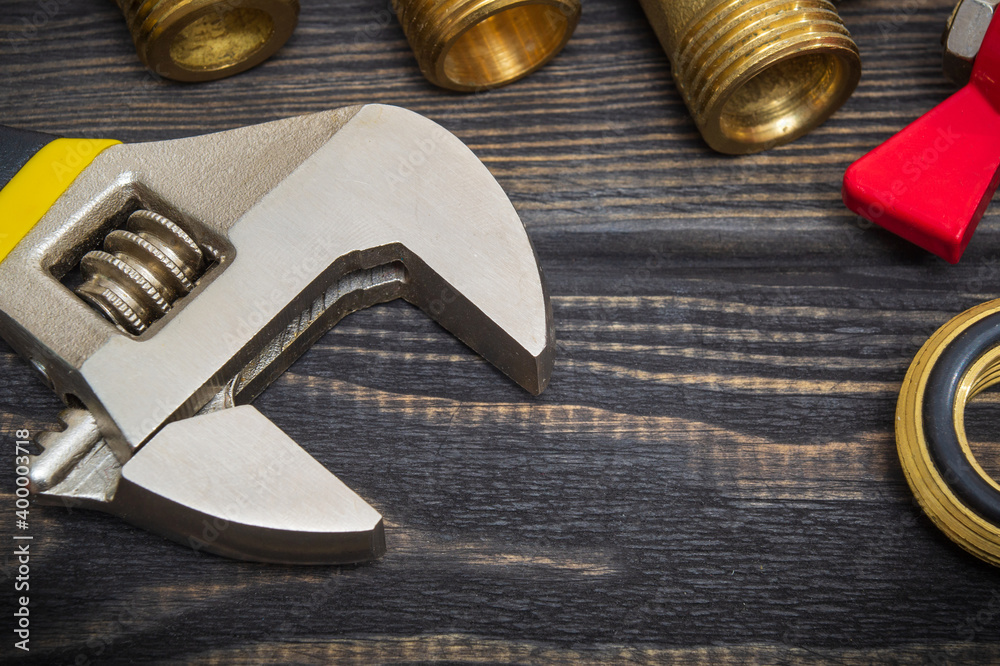 Wall mural adjustable wrench and brass fittings on black boards closeup. plumbing repair idea