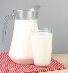  A jug and bottle of milk glass on a wooden table on background.Raw milk is high in calcium and protein to drink for all ages.Milk consumption nutritious and healthy dairy products concept..