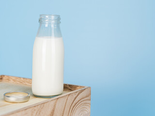  Bottles with fresh milk on a wooden table on a blue background..Raw milk is high in calcium and protein to drink for all ages..Milk consumption nutritious and healthy dairy products concept.