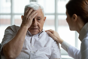 Attentive young lady physician interview senior patient on meeting listen to complaints make diagnosis. Stressed sad elderly man visit trusted capable doctor feel headache dizzy problems with memory