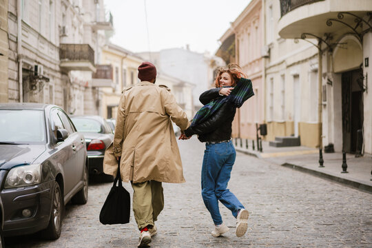 Multinational couple holding hands together and smiling while walking