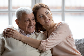 Affectionate grownup daughter embrace retired elderly dad sharing optimism positive emotions. Tender young woman hug beloved old grandfather dreaming together of good happy future long healthy life
