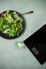 Black scales and salad in a plate on a blue background
