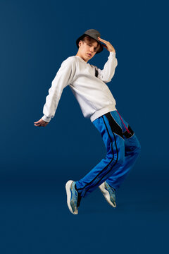 Balancing. Old-school fashioned young man dancing isolated on blue studio background. Artist fashion, motion and action concept, youth culture, fashion returning. Young caucasian curly boy.