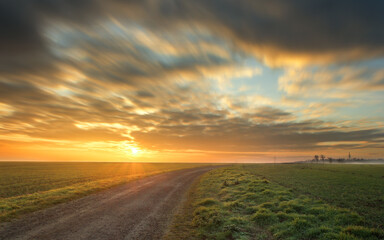 Herrlicher Sonnenaufgang auf dem Feld. Weg zur Sonne. Ein Morgen auf dem Feld. Wolkiger Himmel. Sonnenstern. 