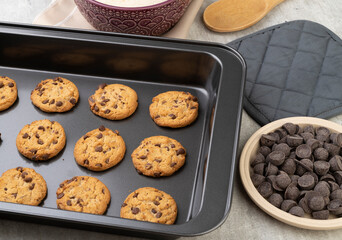 Chocolate chip cookies on a baking tray with ingredients