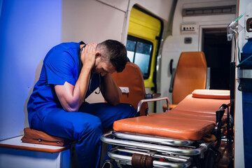 Exhausted paramedic having a little break, sitting in an ambulance car.