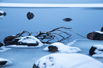 frozen blue lake, frozen rocks in the lake, snow on the rocks