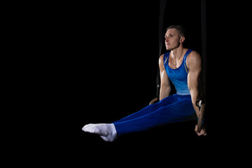 Fototapeta na wymiar Balance. Muscular male gymnast training in gym, flexible and active. Caucasian fit guy, athlete in blue sportswear doing exercises for strength, balance. Movement, action, motion, dynamic concept.