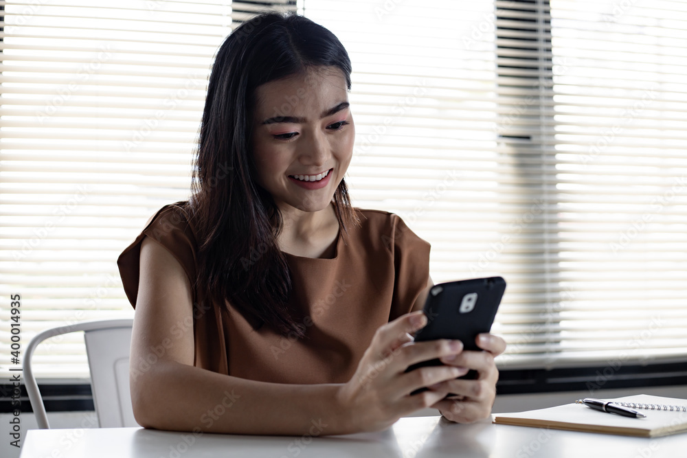 Wall mural asian young woman playing social online on mobile with happy smile.