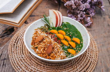 Matcha green tea breakfast superfoods smoothies bowl topped with chia, flax and pumpkin seeds, bee pollen, granola, coconut flakes, almonds and apple for healthy vegan. top view, flat lay