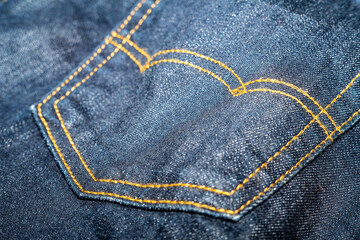Close up detail of back pocket of light blue jeans denim selective focus.
