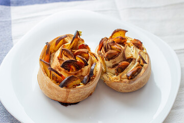 Handmade cinnamon and apple buns on a white plate.
