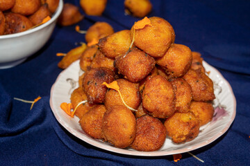 Sugar palm fritters or taler bora in a white Plate on blue cloth background with marigold petals.