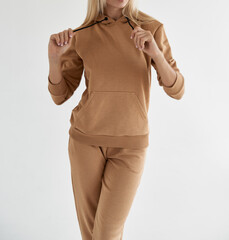 girl wears light brown hoodie and pants. isolated photo of women wearing nude color fleece textile...