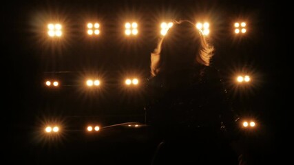 Silhouette of a girl dancing on the background of bright lights on the stage of a night club