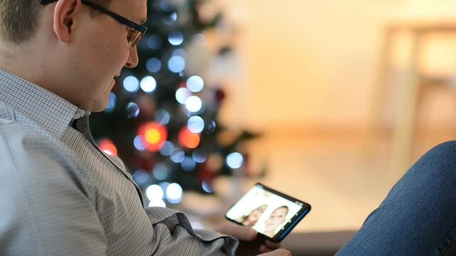 Young father making a video call with his son and daughter using smartphone
