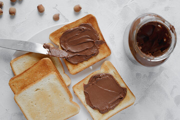 Bread toast with chocolate-nut paste spread and a jar with a knife