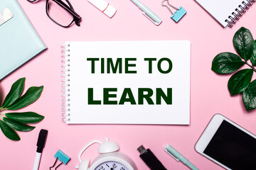 TIME TO LEARN is written in a white notebook on a pink background surrounded by business accessories and green leaves.