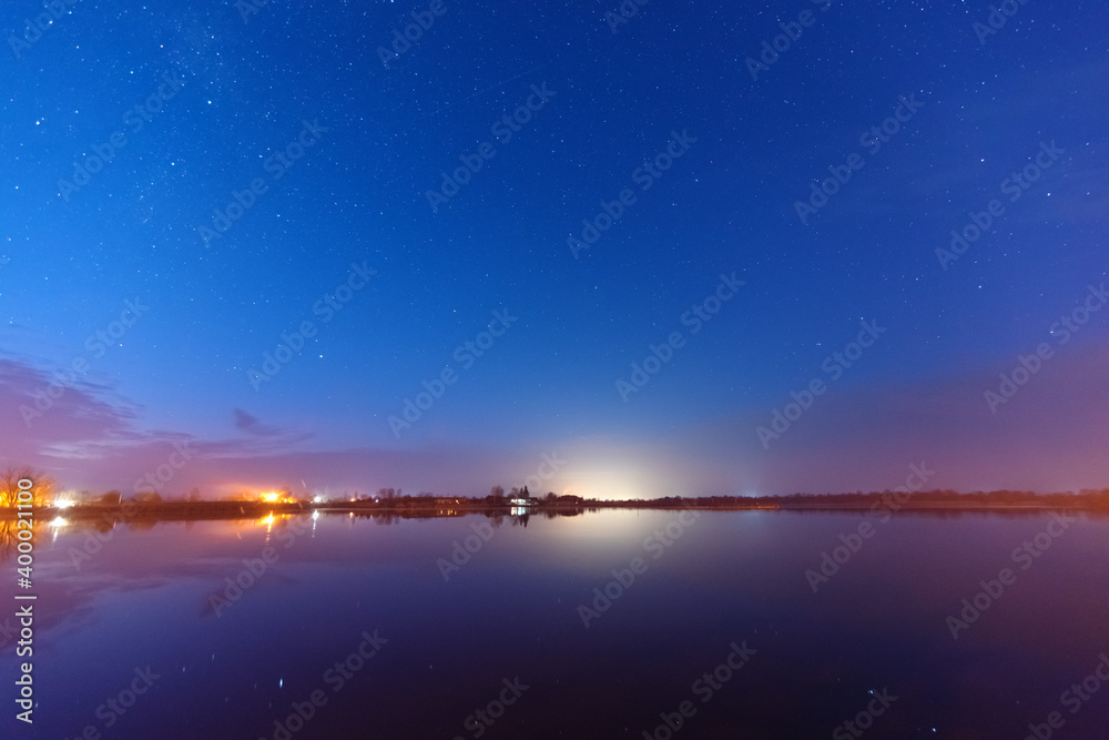 Wall mural a magical starry night on the river bank with a large tree and a milky way in the sky and falling st
