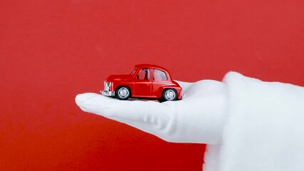 Santa Claus hand holding small red toy car
