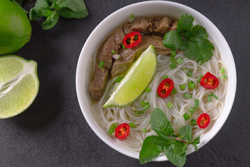 Pho Bo - Vietnamese fresh rice noodle soup with beef, herbs, lime and chili. Vietnamese national dish.