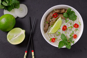 Pho Bo - Vietnamese fresh rice noodle soup with beef, herbs, lime and chili. Vietnamese national dish.