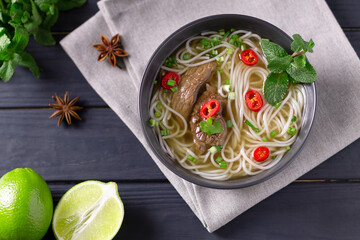 Pho Bo - Vietnamese fresh rice noodle soup with beef, herbs, lime and chili. Vietnamese national dish. Top view.