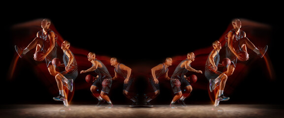 Young purposeful basketball player training in action on black background with fire flames. Mirror,...