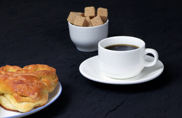 Pastry and cup of coffee on a black background. Homemade cake. Cane sugar. Fresh baked cake. Breakfast